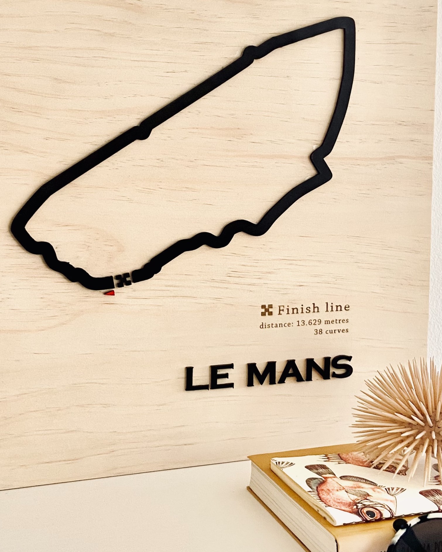 Quadro decorativo de parede em madeira com o contorno do Circuito de Le Mans (preto) e o nome da pista em relevo, com detalhes da linha de chegada e estatísticas.