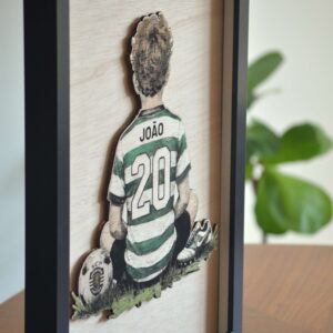 Quadro de parede personalizado Novas Lendas com moldura preta, representando um jogador de futebol em madeira.