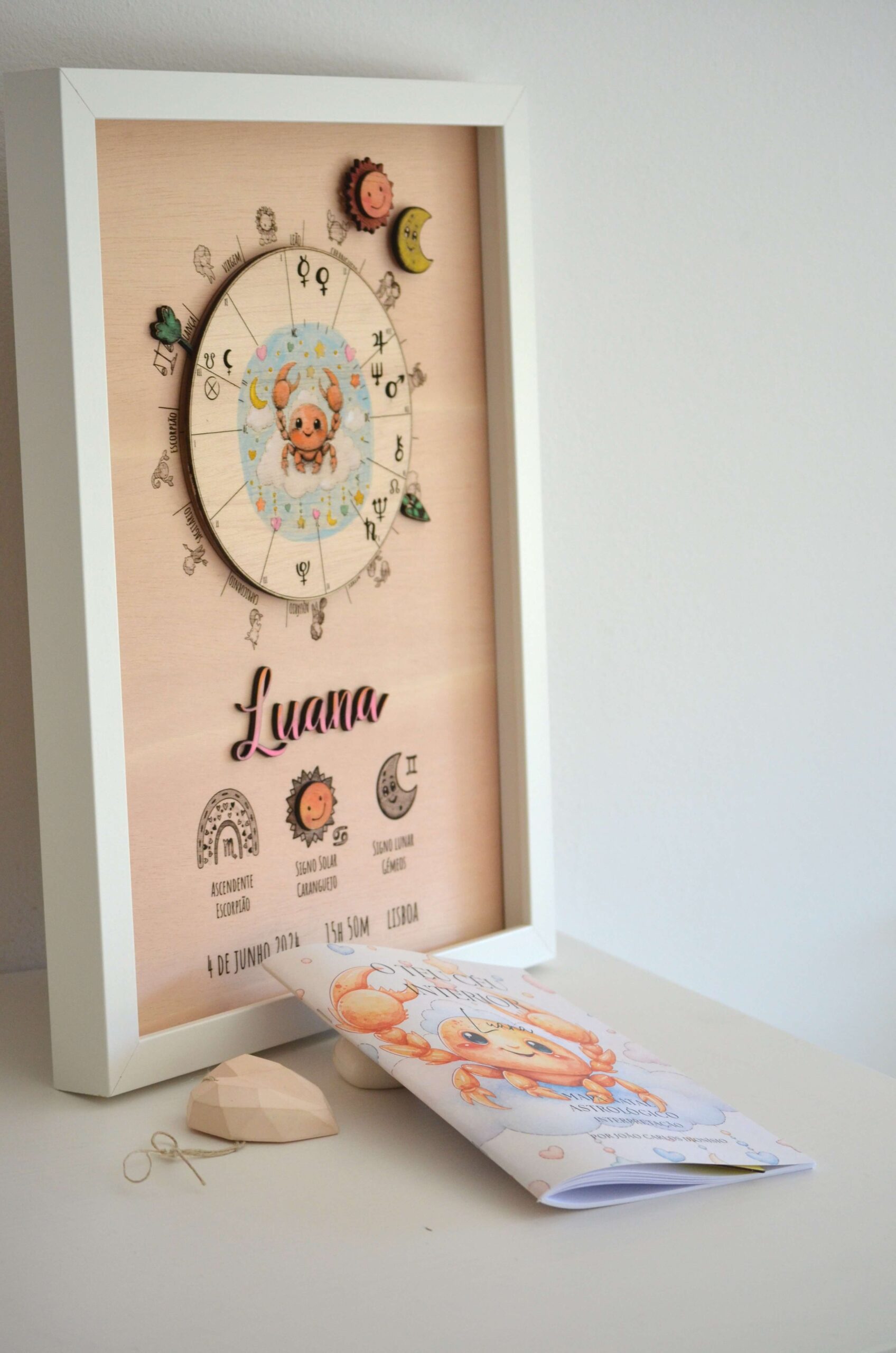 Quadro de mapa astrológico infantil em madeira personalizado com o nome Luana e o livro de interpretação "O Teu Céu Interior" em primeiro plano, da Pinóquio Woodart.