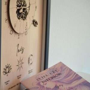 Quadro de mapa astrológico em madeira da Pinóquio Woodart com o nome Inês, acompanhado pelo livro de interpretação "O Teu Céu Interior" em primeiro plano.